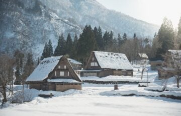雪に包まれた五箇山の合掌造りの家々と冬の山