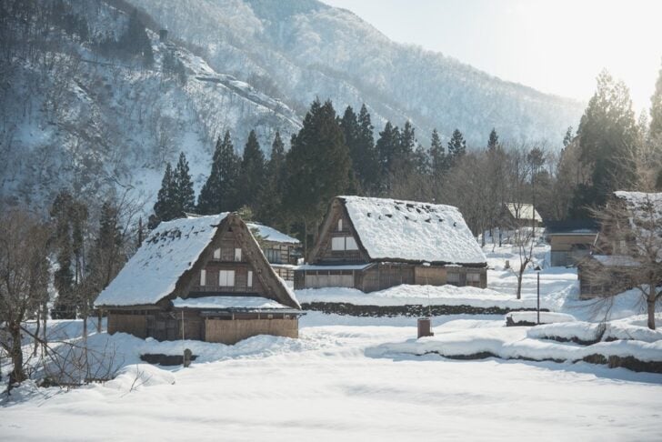 雪に包まれた五箇山の合掌造りの家々と冬の山