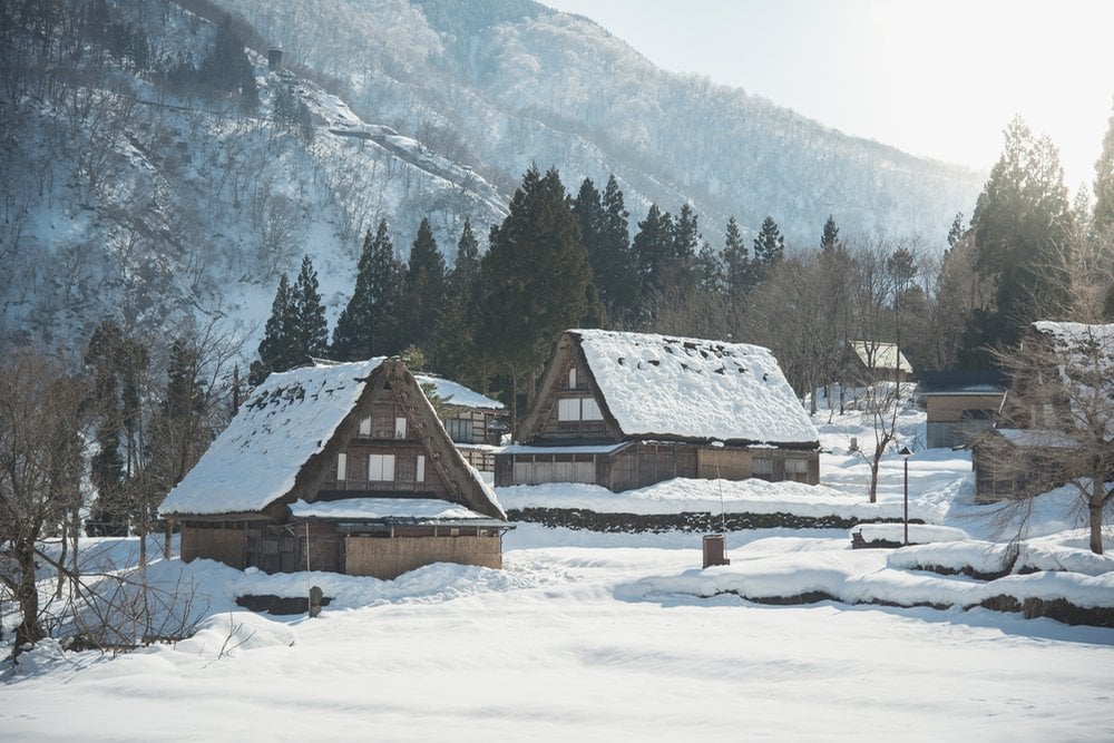 雪に包まれた五箇山の合掌造りの家々と冬の山