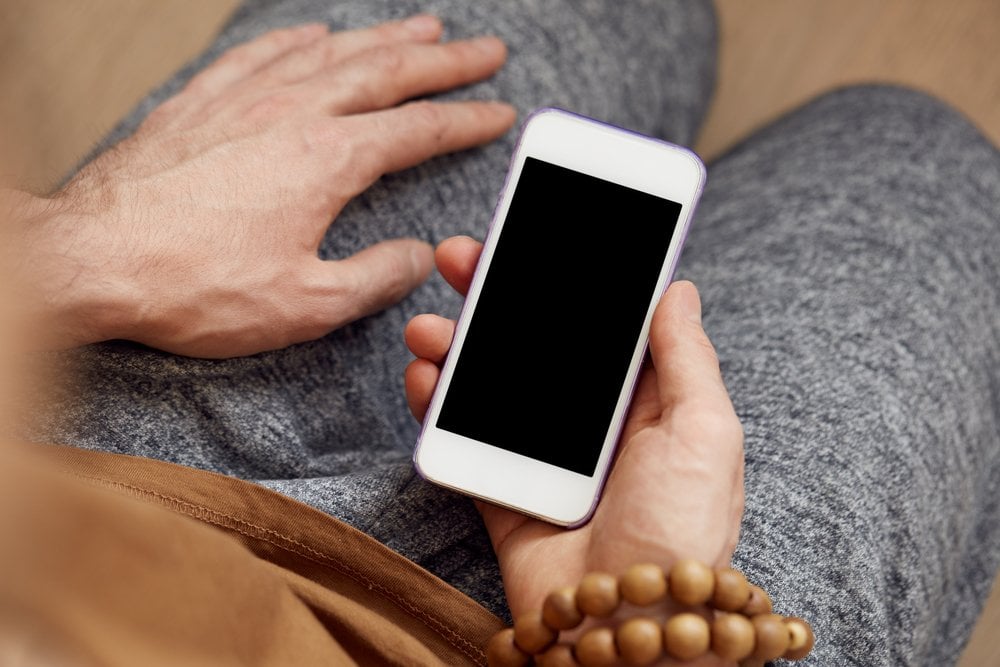 膝の上でスマートフォンを手に持つ人の手元