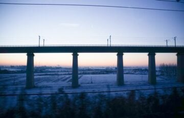 列車の窓から見た雪原と高架橋、夜明けの空