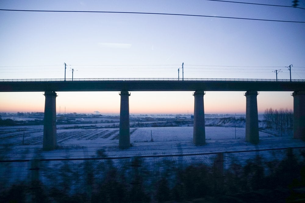 列車の窓から見た雪原と高架橋、夜明けの空